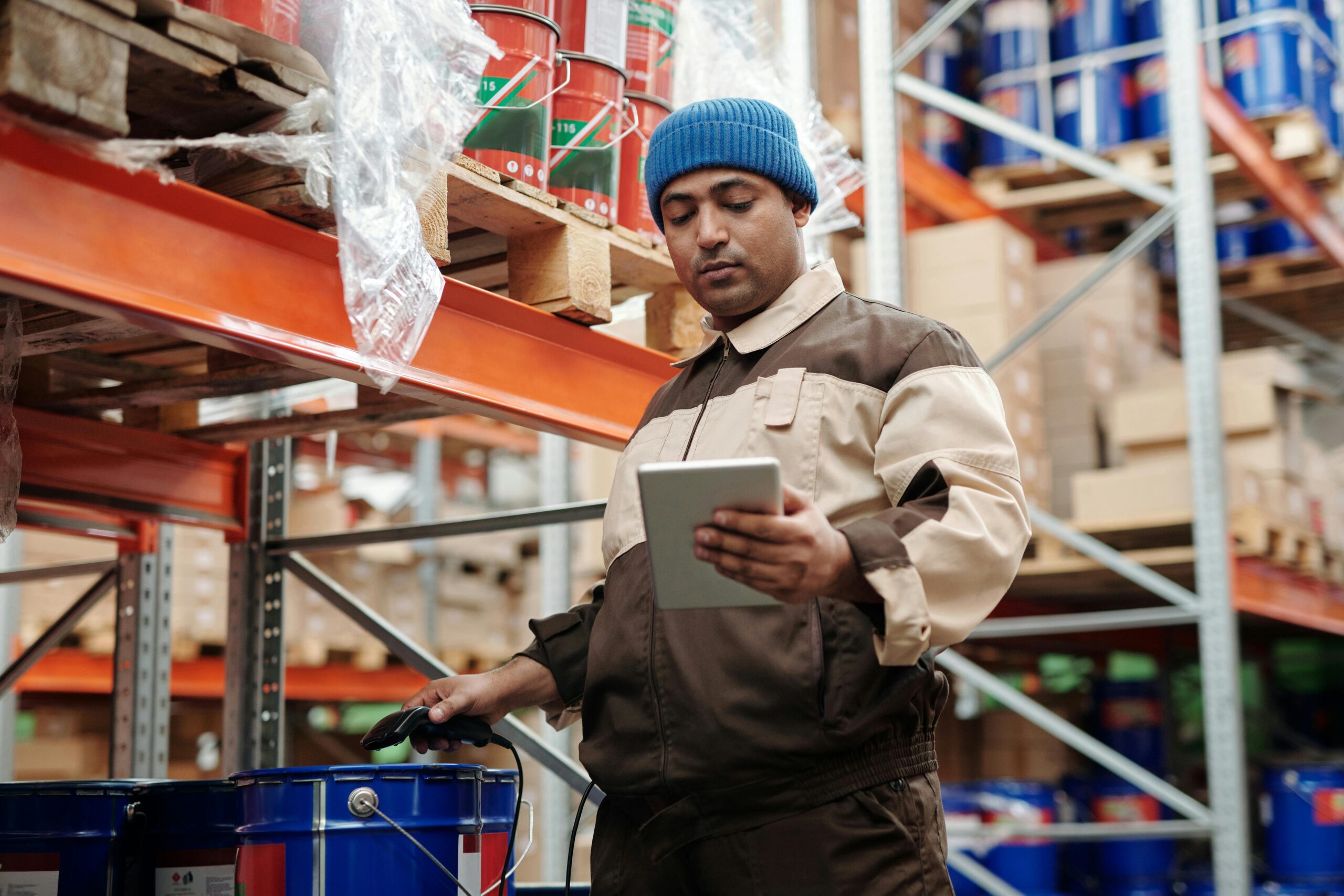 Trabajador gestionando inventarios en un almacén mediante un ERP logístico en una tablet